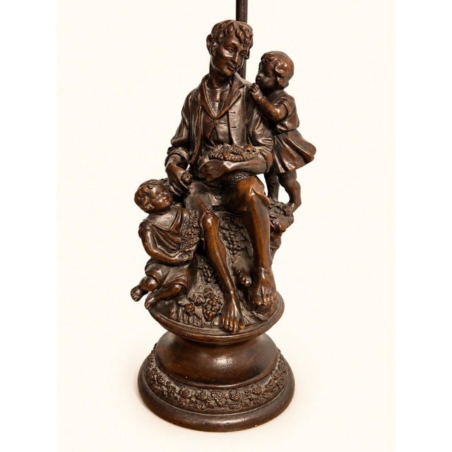 A dark brown patinated spelter table lamp, imbued with the poetic charm of the late 19th century. Its sculpted stem...