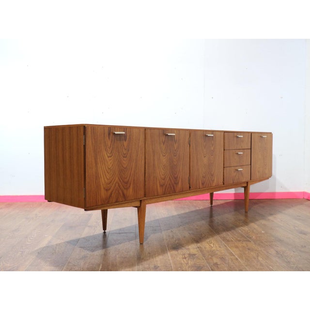 A stunning sideboard by renowned British furniture maker Wrighton, this Mid Century Modern Vintage Teak Sideboard Credenza...