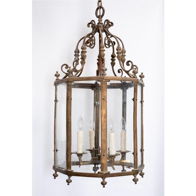 A large, octagonal lantern with glass enclosure, c. 1900, French. Frame, finals, and scrollwork are solid brass. Glass...