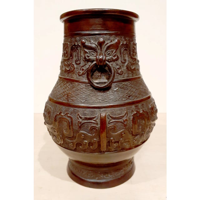 Chinese bronze two handled Hu, archaic Chinese symbols in low relief on the body, floral band in low relief at the foot,...