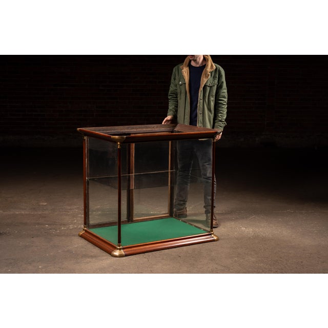 Compact countertop display case constructed in richly toned mahogany with rounded brass corner caps and vertical supports....