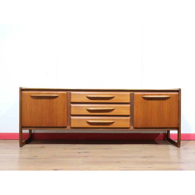 A stunning piece of furniture with sleek mid century style, this Vintage Teak British Credenza Sideboard in the manor of...