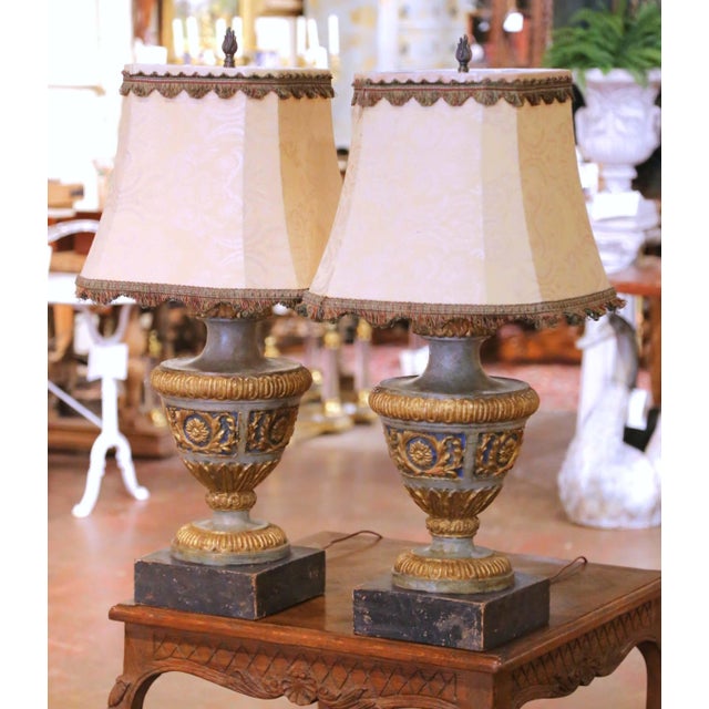 Elegant pair of Italian carved and painted table lamps crafted circa 1950, each designed in a classical urn form with...