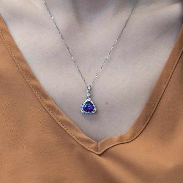 A rich purple amethyst pendant cut in a fancy trillion shape with a natural diamond halo for a lovely added shine! If you...