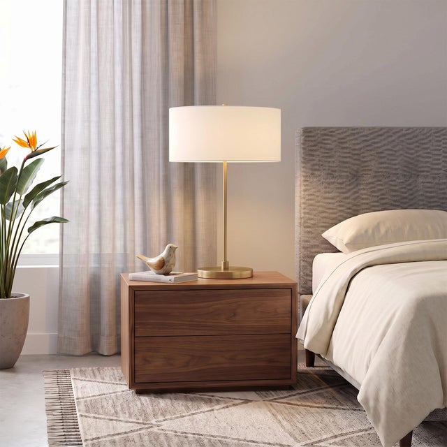 The Stretch Slimline Table Lamp is a modern table lamp featuring a weathered brass steel body and a drum white linen...