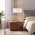 The Stretch Slimline Table Lamp is a modern table lamp featuring a weathered brass steel body and a drum white linen...