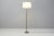 A Mid-Century French floor lamp with a blackened steel shaft and base, with brass details at the base and neck. Double...