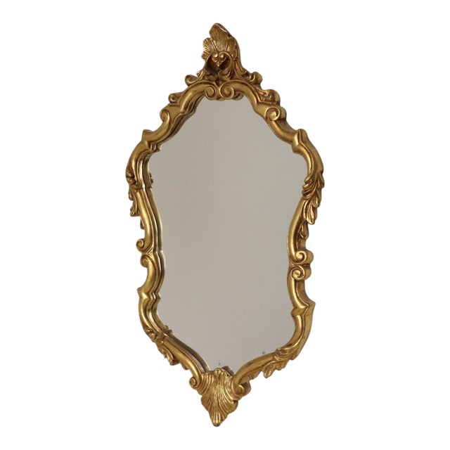 French vintage gold-tone mirror featuring a decorative crest and acanthus leaf detailing; the frame is made of plaster and...