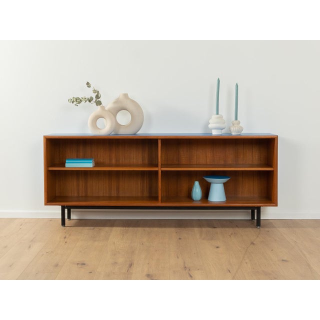 Wonderful sideboard from the 1960s. The body is made of teak veneer with two shelves and new black square steel feet. The...