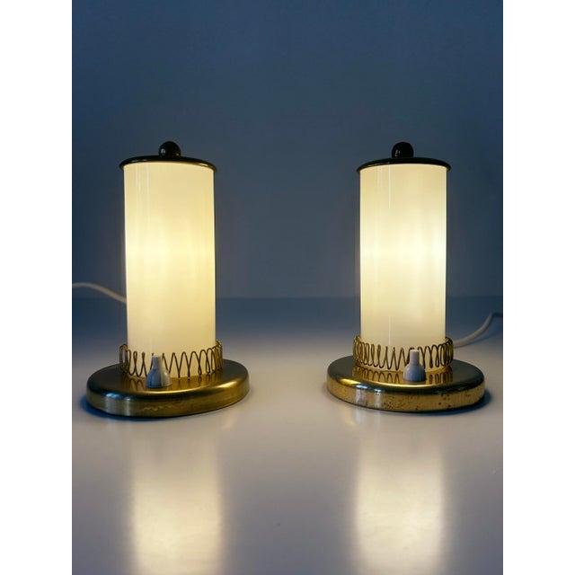 Set of two rare, lovely and highly decorative mid-century modern brass and opaline glass bedside table lamps. Designed and...