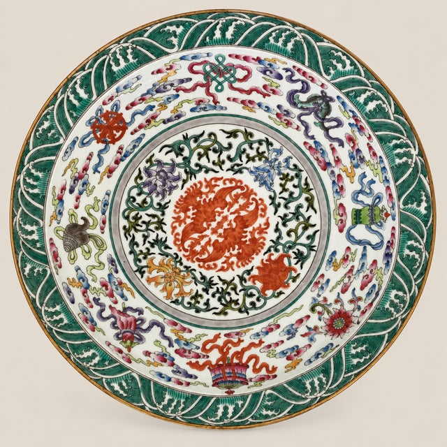 The wide, heavily potted dish is brightly enamelled to the centre with confronting phoenix surrounded with a lotus flower...