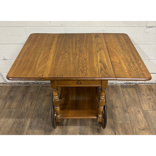 This is a beautiful vintage oak drop leaf bar cart or tea cart. It features a full sized bottom shelf, a cart handle,...