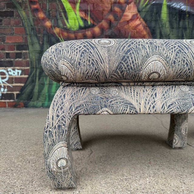 This is a pair of vintage oriental style cushioned ottoman’s covered in a navy and tan peacock patterned fabric.