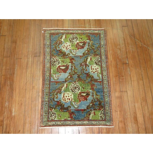 An early 20th century Persian Senneh rug featuring a Gol- Farang design, dominant accents in sky blue and chartreuse....