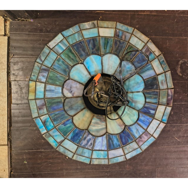 The shade features a nautical theme with sailboats, a sun, and sky scenes in shades of blue, green, and pink. The lamp is...