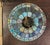 The shade features a nautical theme with sailboats, a sun, and sky scenes in shades of blue, green, and pink. The lamp is...