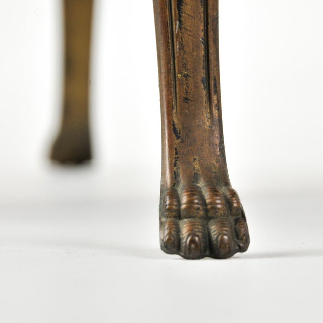 A unique petite footstool that will add interest to any eclectic home. Four elongated brass feet hold a round wood top...