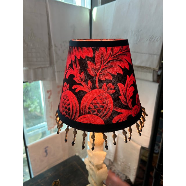 A small clip top shade handmade from an antique French printed cotton, embellished with wooden beaded fringe, 2 are...