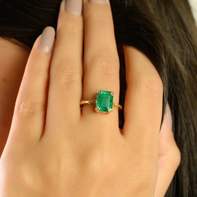 This elegant ring showcases a 2-carat emerald-cut natural emerald, set in a classic double-prong setting that highlights...