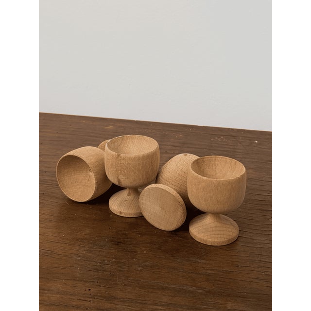 Set of four small egg cups, each turned from light hardwood with a simple goblet shape and rounded foot.