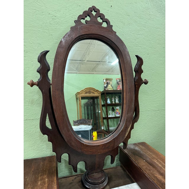 A stunning Victorian rosewood three-drawer dresser with oval swivel mirror. The mirror has an ornate scalloped frame and...