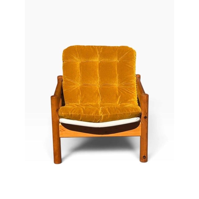A chunky, sun-warmed Danish modern lounge chair built from solid pine, with thick round post legs and broad flat arm rails...