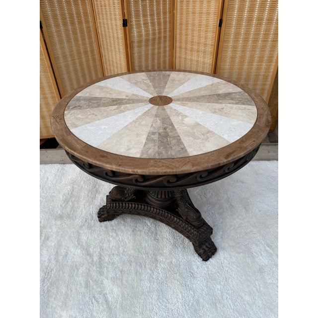 Beautiful round center table with a marble inlay top in a sunburst design. The stone pieces show a mix of natural shades...