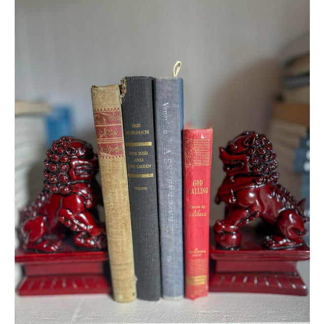 Chinese foo dogs in a rich ox-blood red resin. One lion rests a paw on an embroidered ball (symbolizing power), while the...