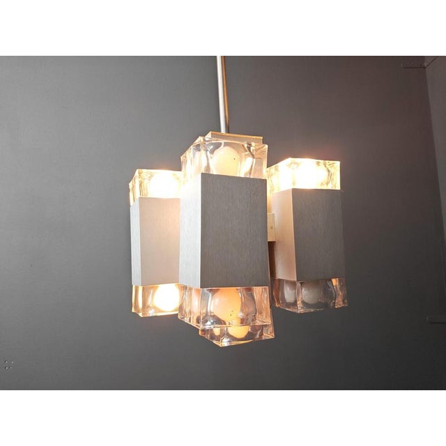 Vintage modernist chandelier in the manner of Gaetano sciolari consisting of an aluminum frame with hand made glass lamp...