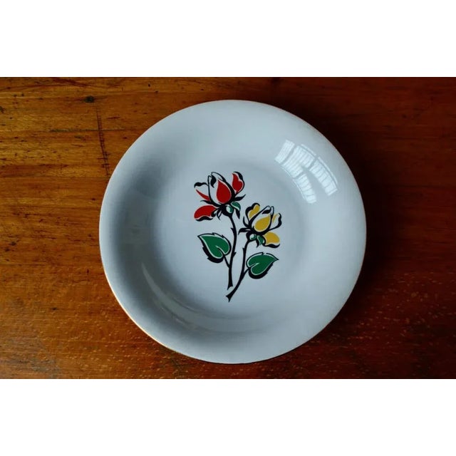 A pretty, brightly-colored floral decoration adorns this antique bohemian dinnerware set, produced by the L'Amandinoise...