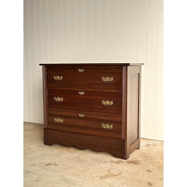 Antique wooden chest of drawers with a solid wood case and three graduated drawers. Original brass hardware and reeded...
