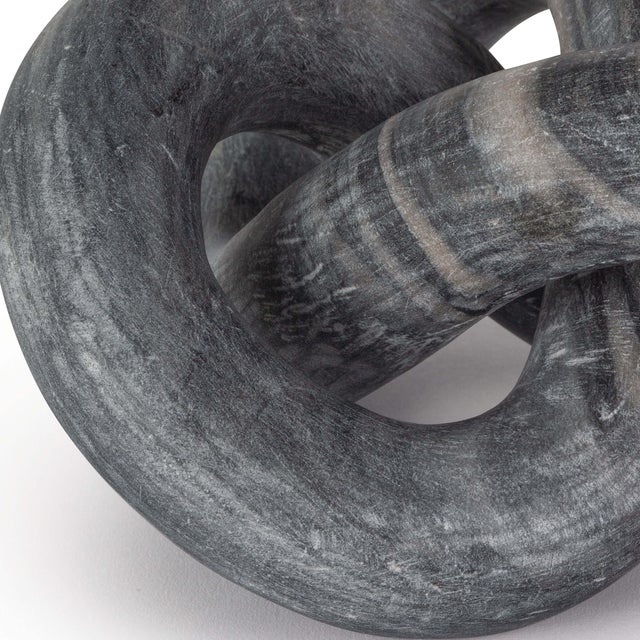 Hand-carved from a single piece of black stone, this abstract sculpture weaves about creating a flowing singular form. Add...