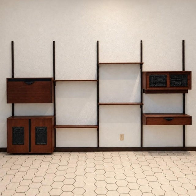 A custom mid-century modern walnut wall unit dating to approximately the 1960s. The modular system combines warm walnut...