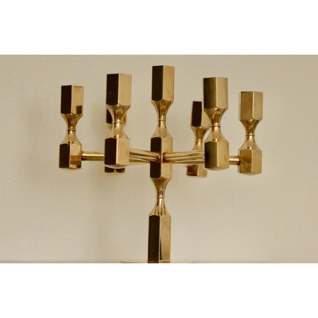 Made in Sweden. This exquisite seven-arm candelabra, crafted from solid brass, is a design masterpiece produced by Gusum...