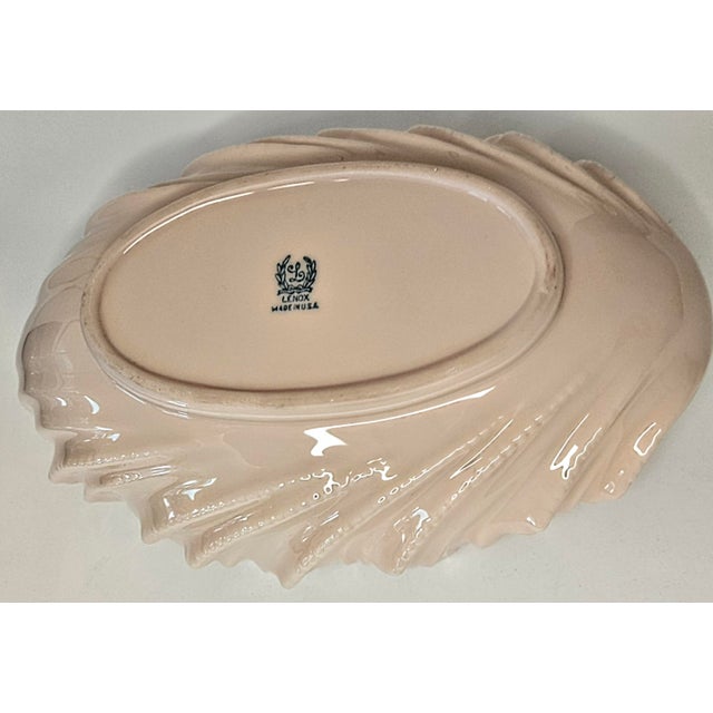 Gorgeous pink waves splash up around a scaled ivory edge on this late 20th century Lenox china piece.