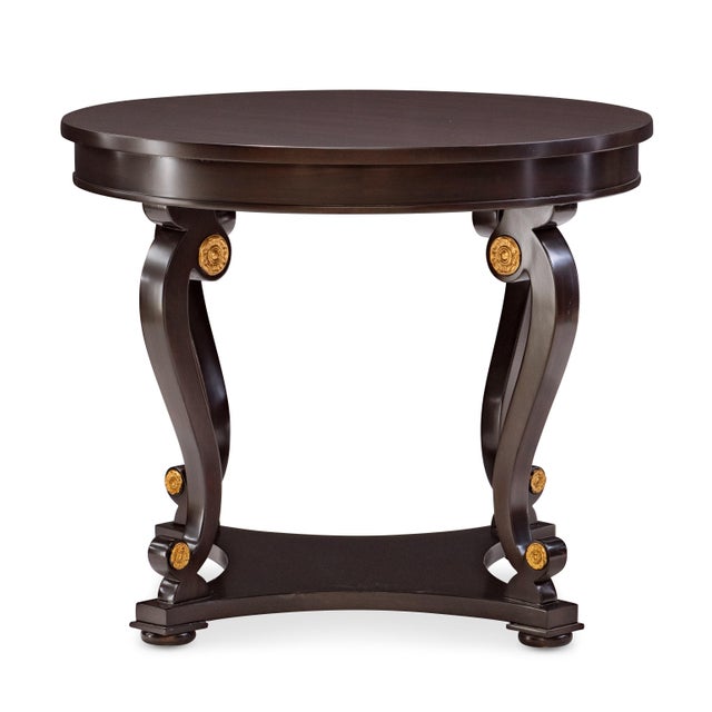 A refined round accent table that balances sculptural form with classical detailing. The curving legs and triangular...
