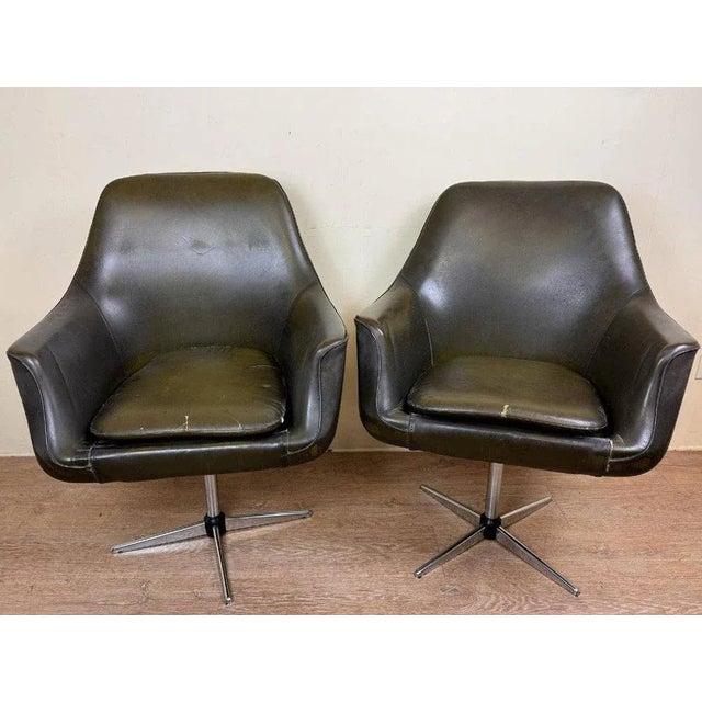 In the style of Overman: Pair of mid-century Swedish swivel armchairs with leather upholstery and seat cushion rest on a...