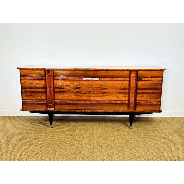 A superb low sideboard, a modernist, late art deco style piece crafted from rosewood veneer with a pronounced and...