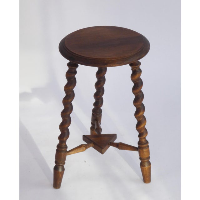 A small rustic wooden side table with barley legs. The small stool has a a round top with beautiful carvings on the edges....