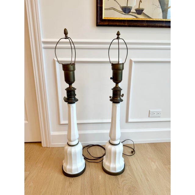 Striking pair of monumental vintage table lamps crafted from molded white milk glass with beautifully aged brass-tone...
