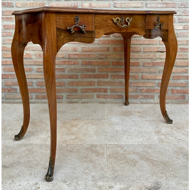 Elegant French writing table crafted in walnut, designed in the Louis XV style. The table features a shaped rectangular...