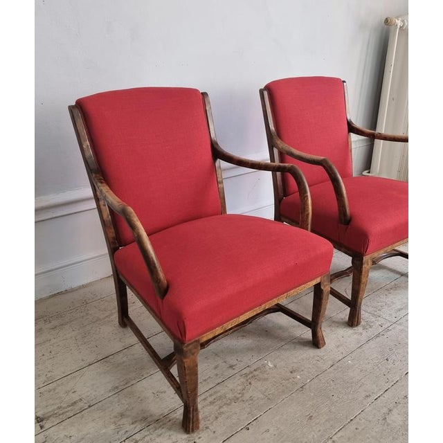 A pair of rare Swedish Grace armchairs in stained beech and red linen/cotton fabric. Paw shaped legs and rounded armrests....