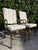 A matched pair of vintage hammered iron lounge chairs featuring sculptural scroll arms, decorative brass finials, and a...