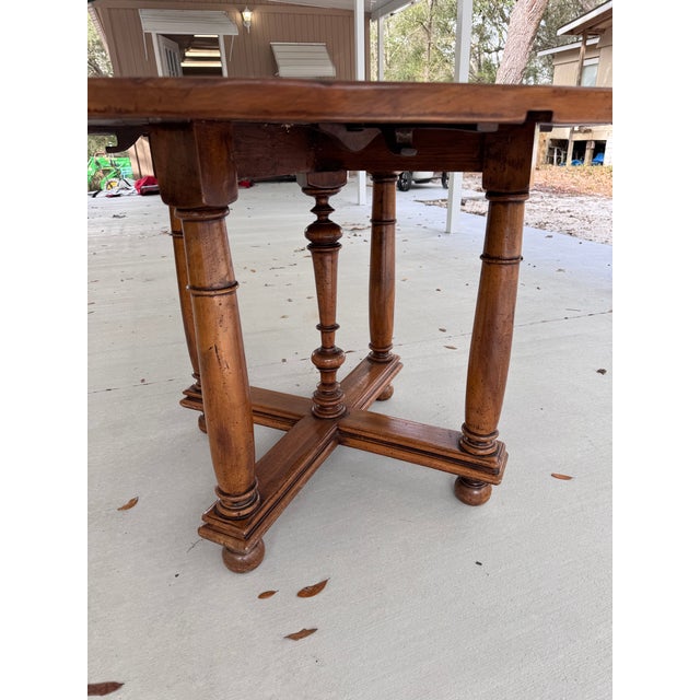 This item is an antique French walnut drop-leaf table featuring a circular top and turned legs with a central stretcher....