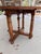 This item is an antique French walnut drop-leaf table featuring a circular top and turned legs with a central stretcher....