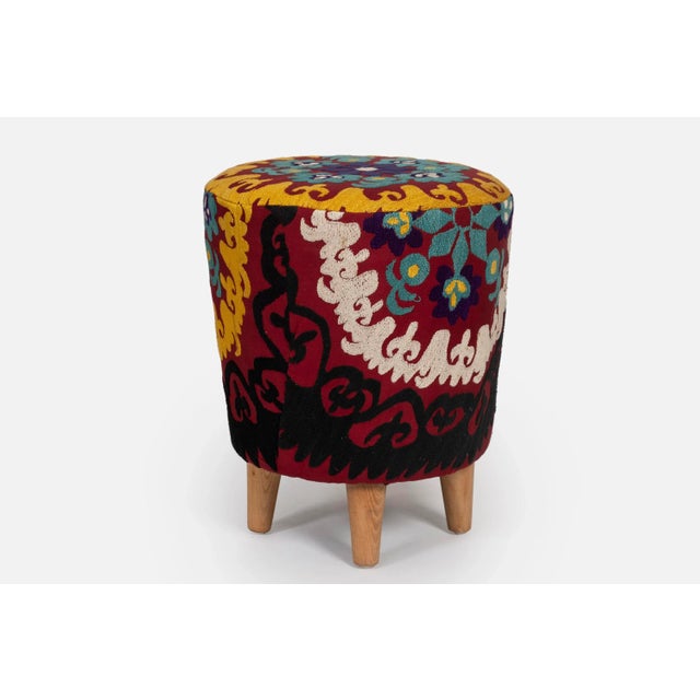 Colorful round ottoman upholstered with vintage Uzbek suzani fabric. This one-off footstool has been lovingly restored...