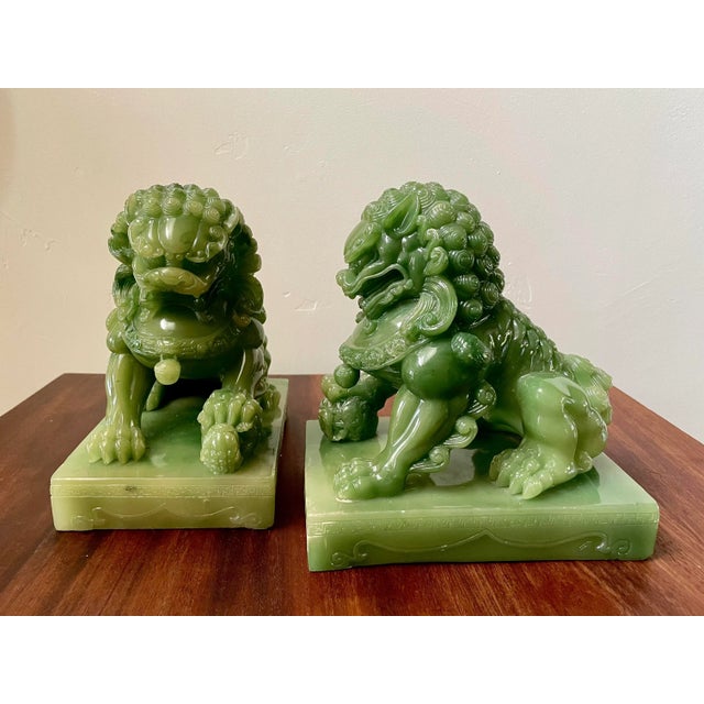 Excellent 1950s, premium-acrylic jade imperial guardian lions; also known as Shishi Lions. The male lion figure rests its...
