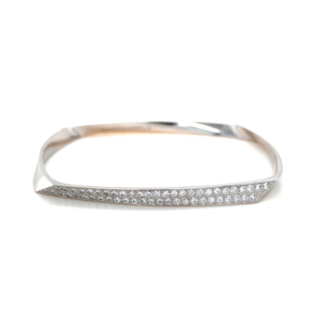This sleek bangle bracelet designed by Frank Ghery for Tiffany & Co. is in a dynamic toque design contains 52 round...