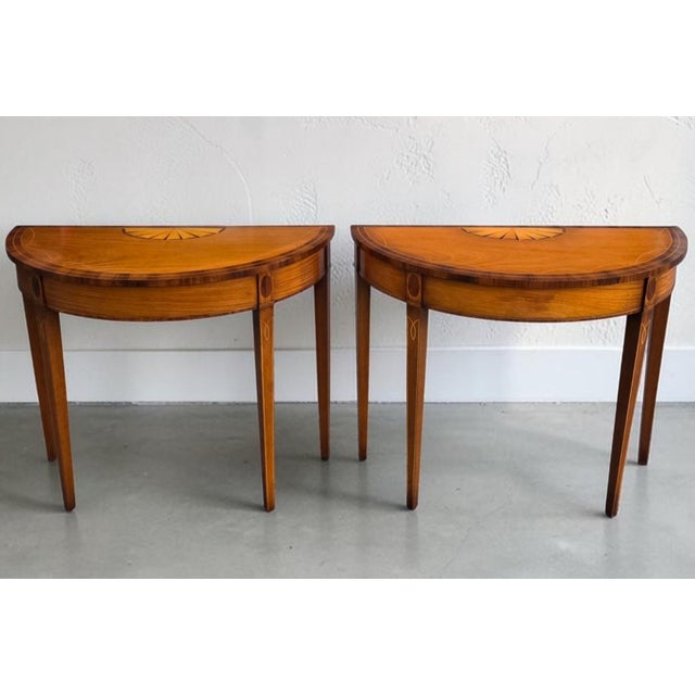 Elegant pair of American Federal Revival mahogany demilune console tables, dating to the mid-20th century, distinguished...