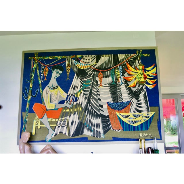 The Net Mender by the renowned mid-20th-century French artist, this colorful textile artwork depicts the daily life of a...